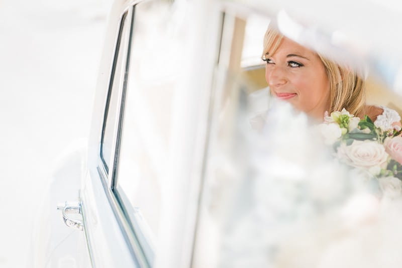 Bride smiling in back of wedding car - Picture by Married to my Camera