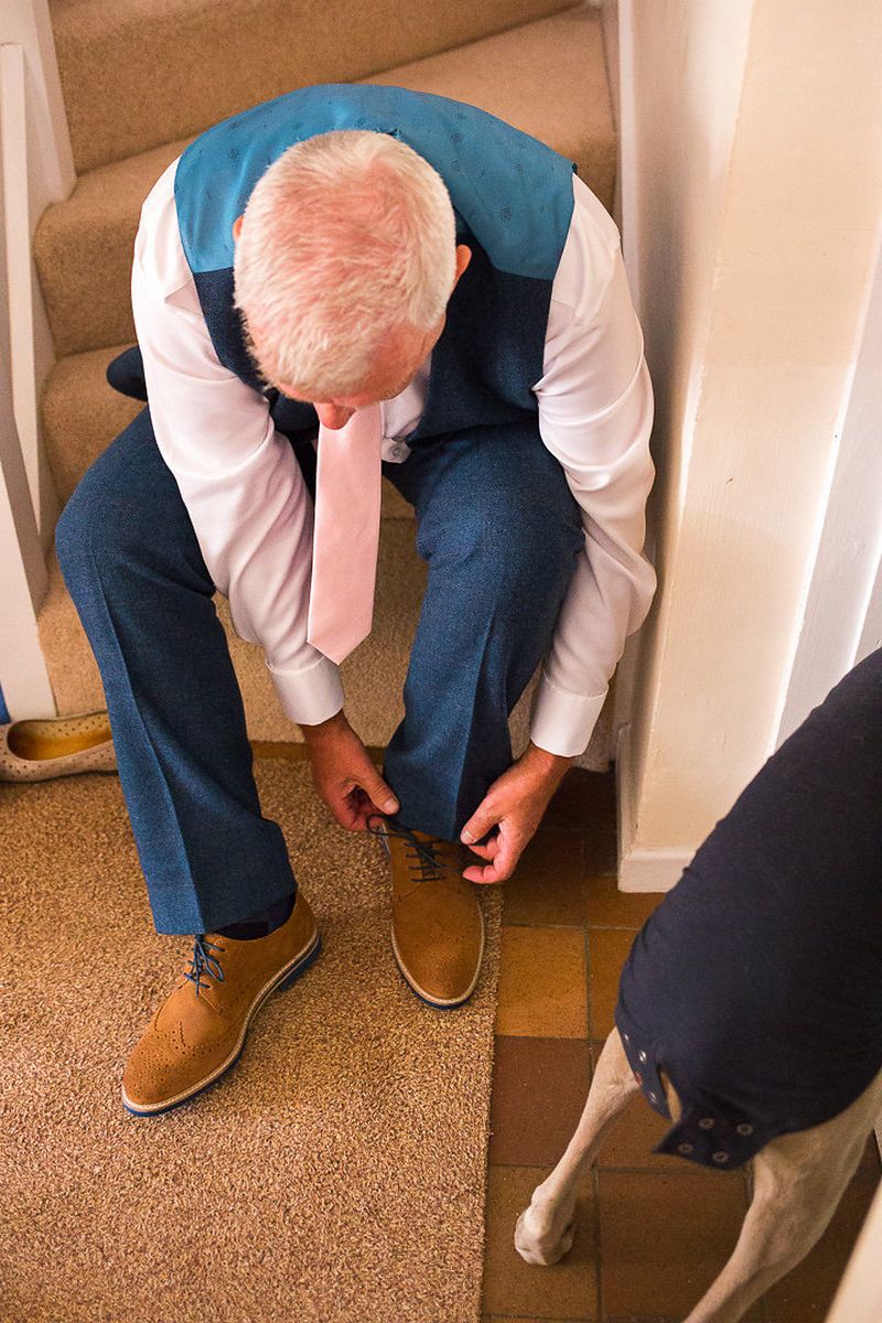 Groom sitting on stairs doing up brown shoes