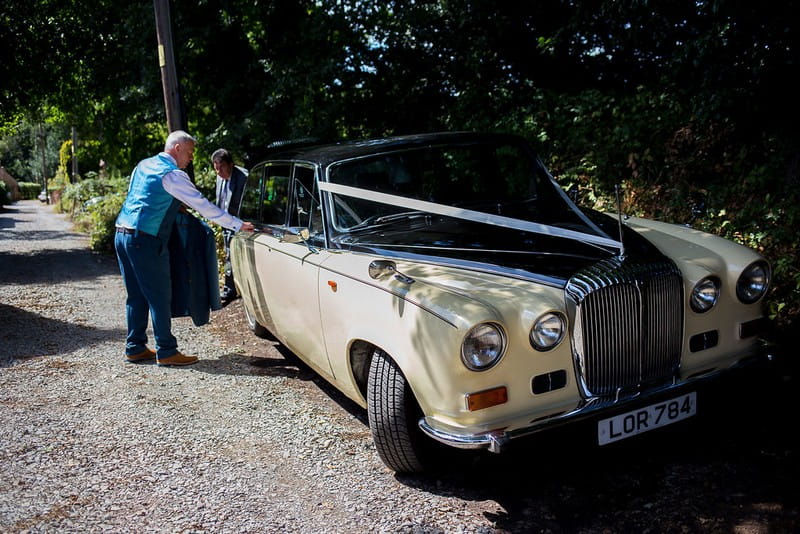 Groom getting into vintage wedding car