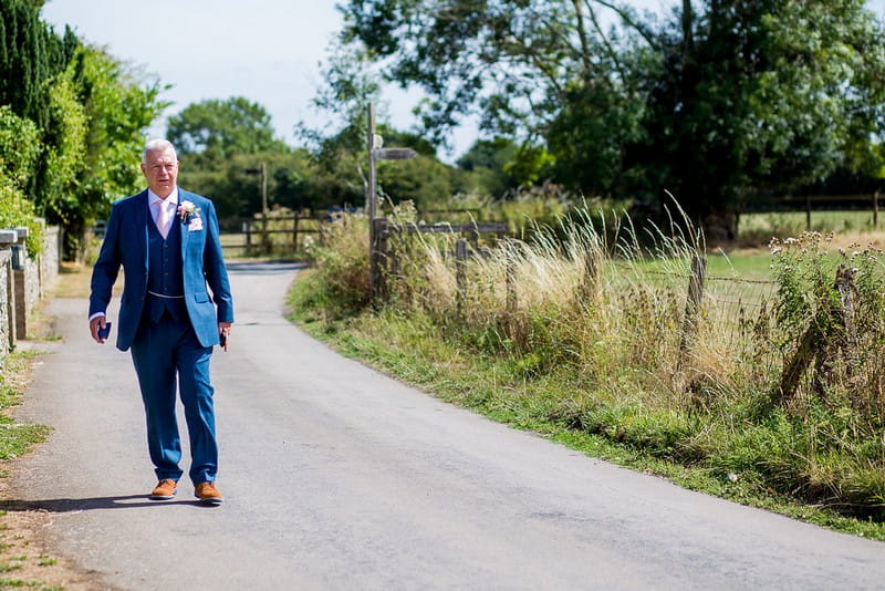 Groom in blue suit walking to wedding