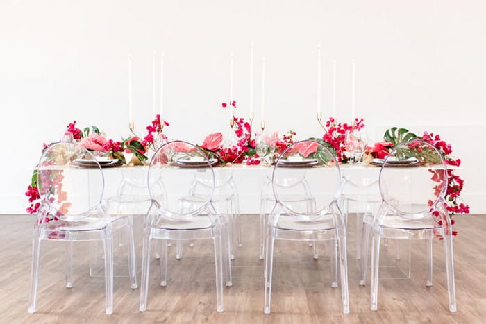 Ghost chairs in front of wedding table styled with bougainvillea