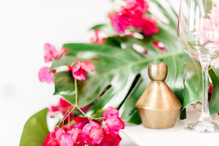 Bougainvillea and tropical palm leaves on wedding table with gold decoration