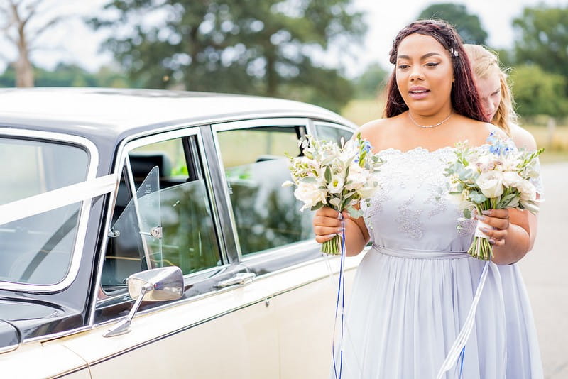 Bridesmaid carrying flowers from wedding car