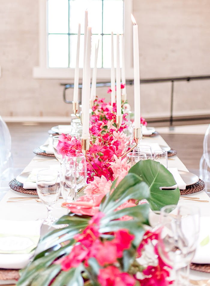 Bright pink bougainvillea and tall candles down centre of wedding table