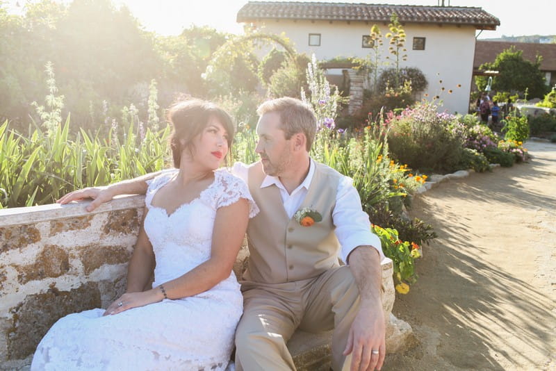 Bride and groom sitting on bench in hazy sunshine