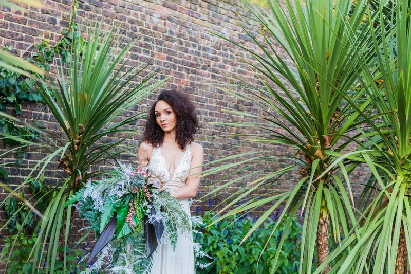 Bride holding tropical bouquet next to long grass plants