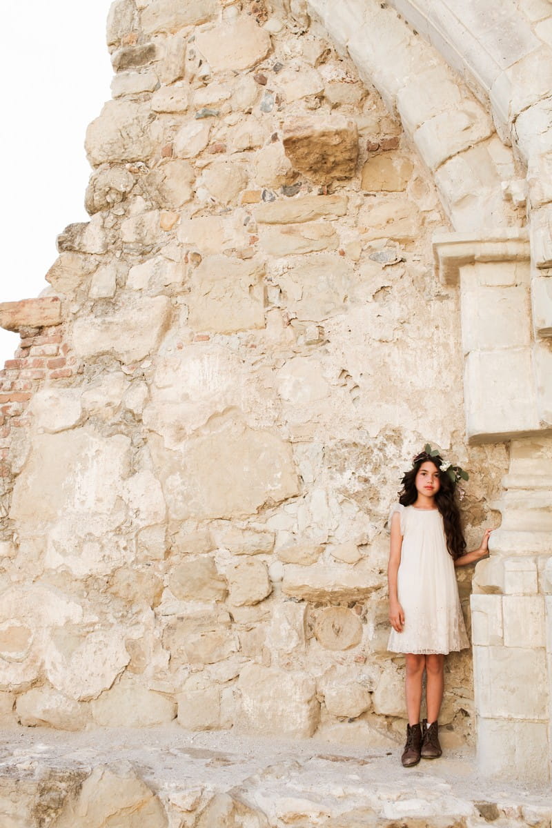 Flower girl standing by rustic wall