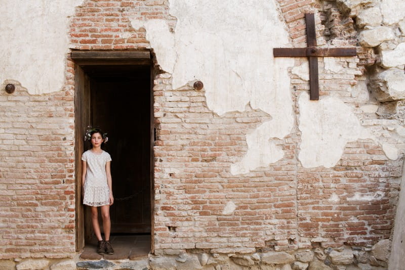 Flower girl standing in doorway of old building