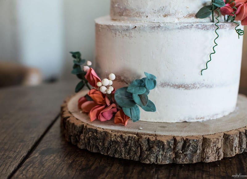 Orange flowers on log slice at bottom of wedding cake