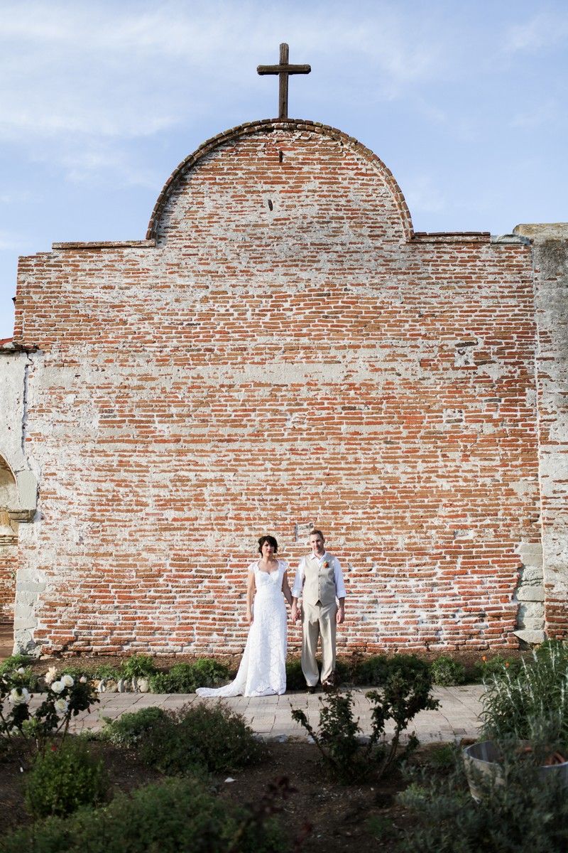 Bride and groom standing in front of wall