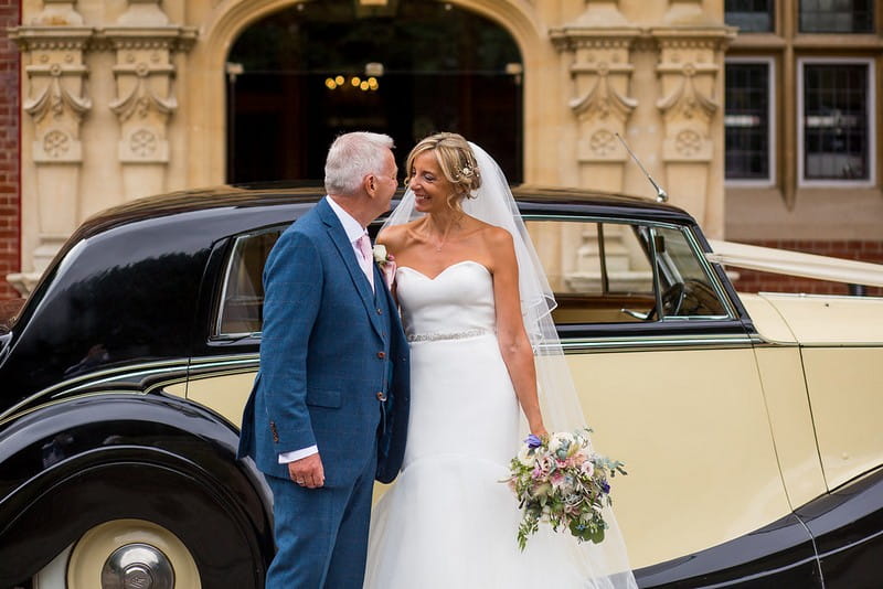 Bride and groom in front of vintage wedding car