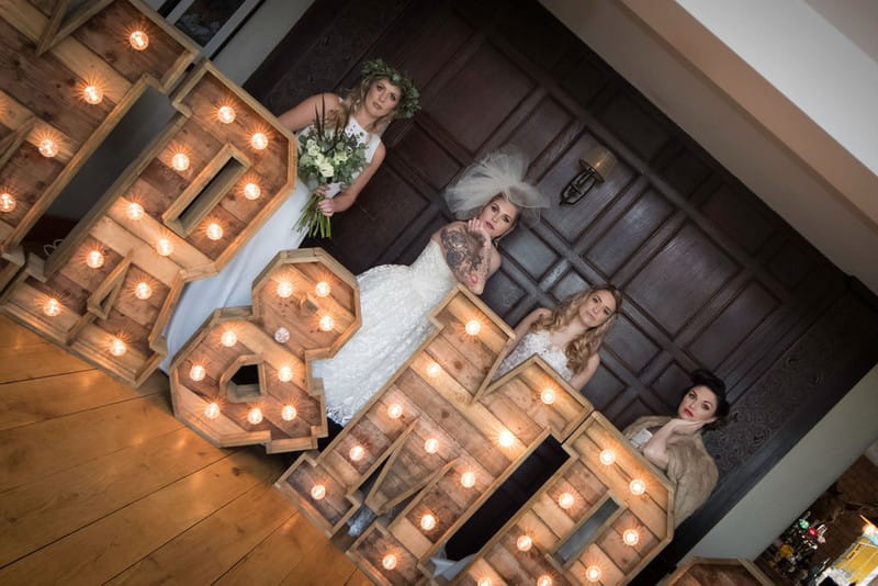 Four brides behind large light up wooden letters