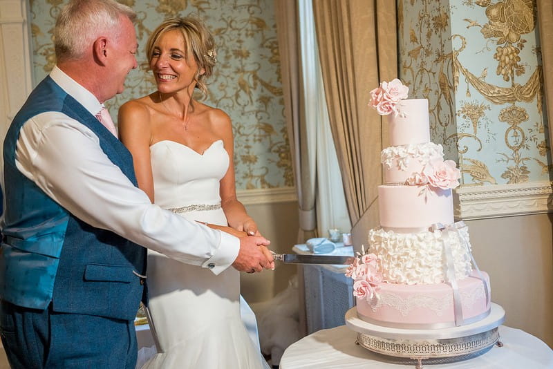 Bride and groom cutting pink wedding cake