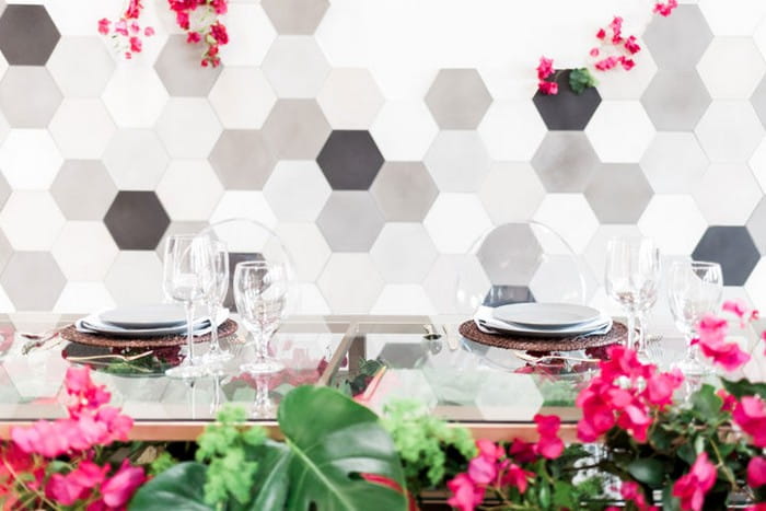 Glass wedding table in front of hexagonal backdrop