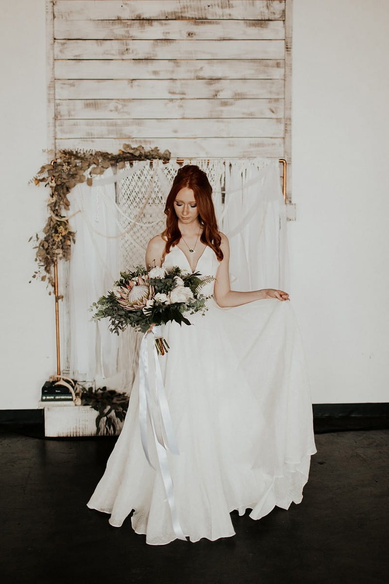 Bride holding bouquet in front of macramé backdrop