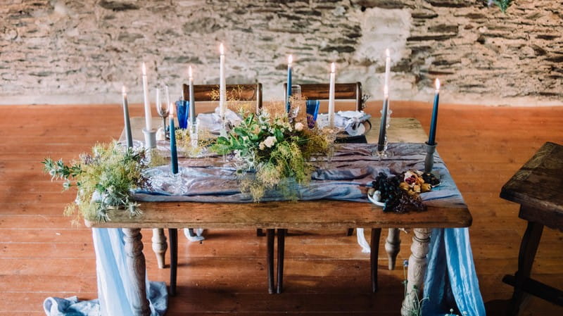 Wedding table styled with rustic blue and grey details and wild flowers and foliage