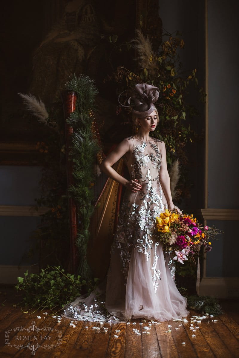 Bride wearing dress with silver detail and grey bridal hat