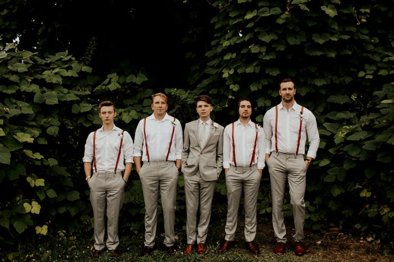 Groom standing with groomsmen wearing shirts and braces