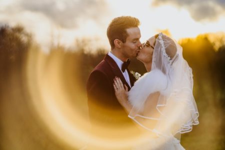 Bride and groom kissing framed in ring of light on camera lens - Picture by Lee Dann Photography