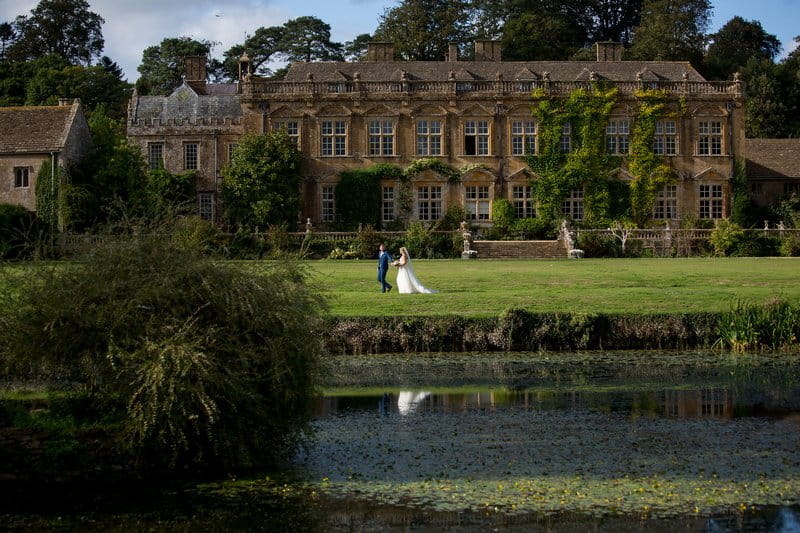 Bride and groom walking by lake in front of wedding venue - Picture by Martin Dabek Photography