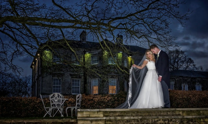 Bride and groom standing under tree in front of wedding venue at night - Picture by Image-i-Nation Photography