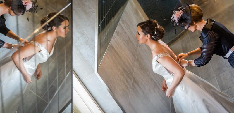 Mother doing up back of bride's wedding dress - Picture by First Light Photography