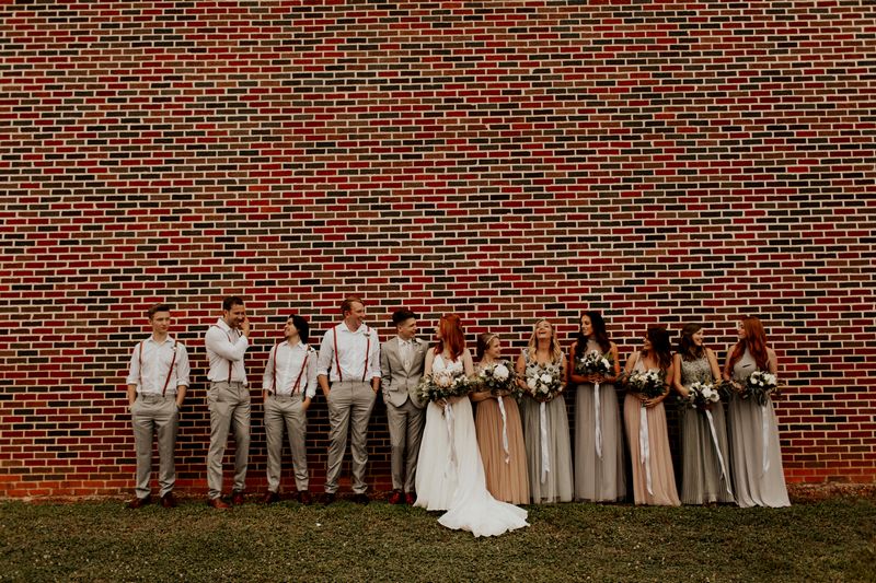 Bridal party standing in front of brick wall