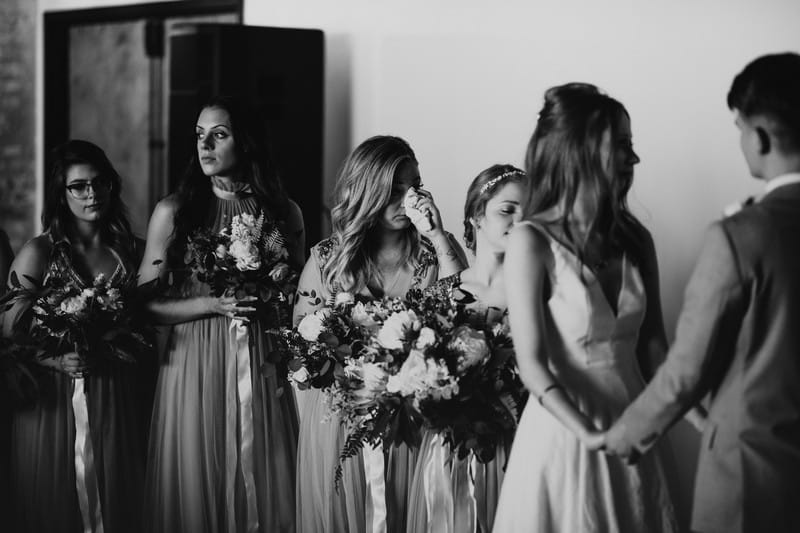 Bridesmaids wiping away tears during wedding ceremony