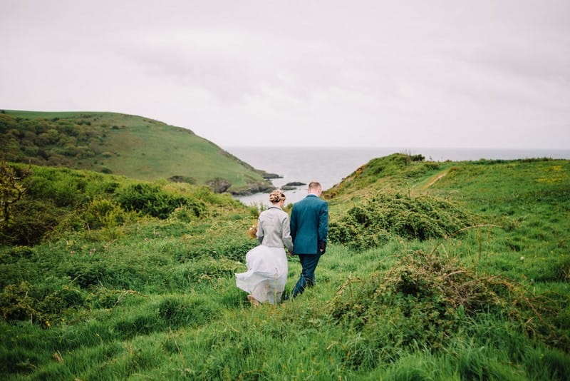 Bride and groom walking on hill by sea