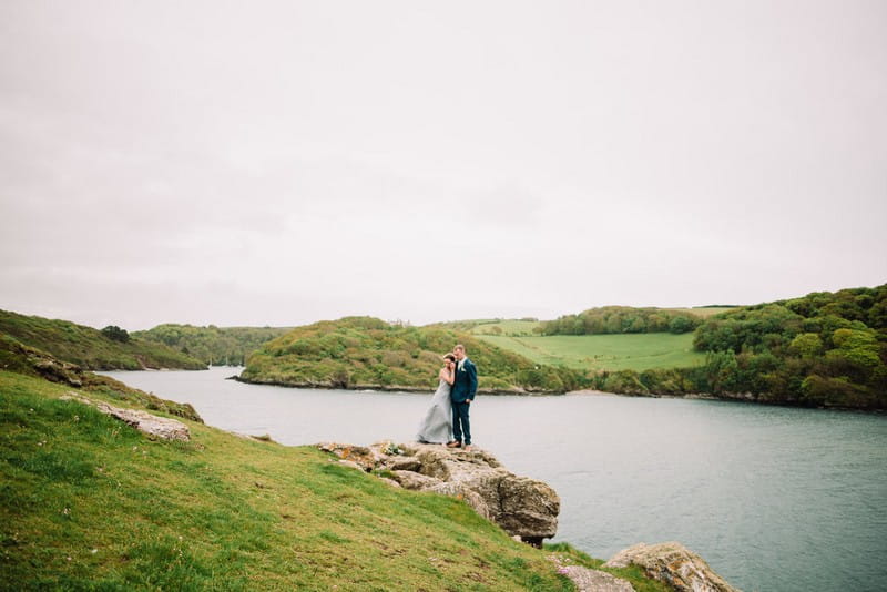 Bride and groom on rock by sea