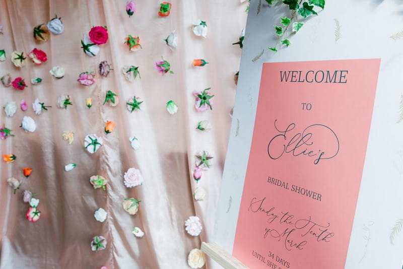 Hanging flower backdrop next to bridal shower welcome sign