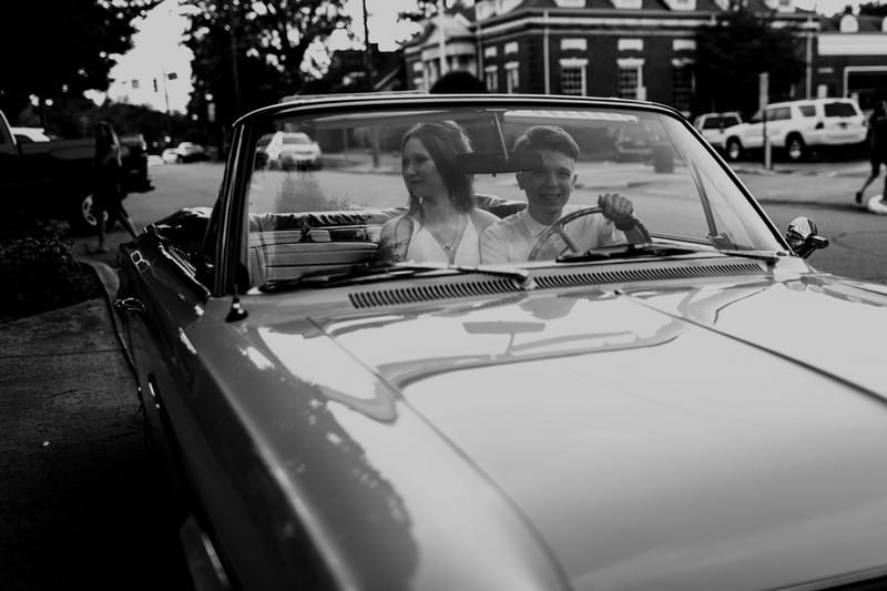 Bride and groom sitting in 1964 convertible Rambler