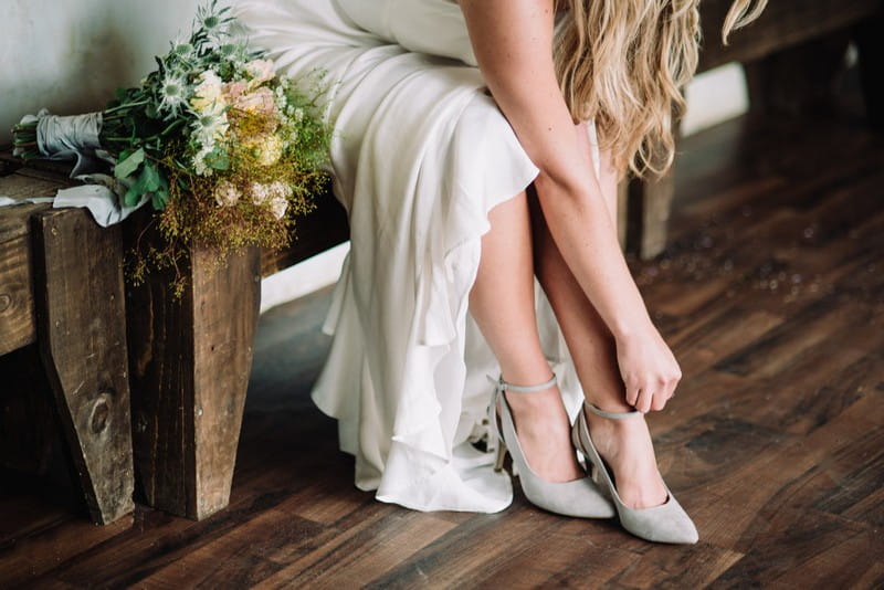 Bride putting on grey shoes