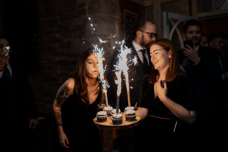 Woman blowing sparklers on cupcakes