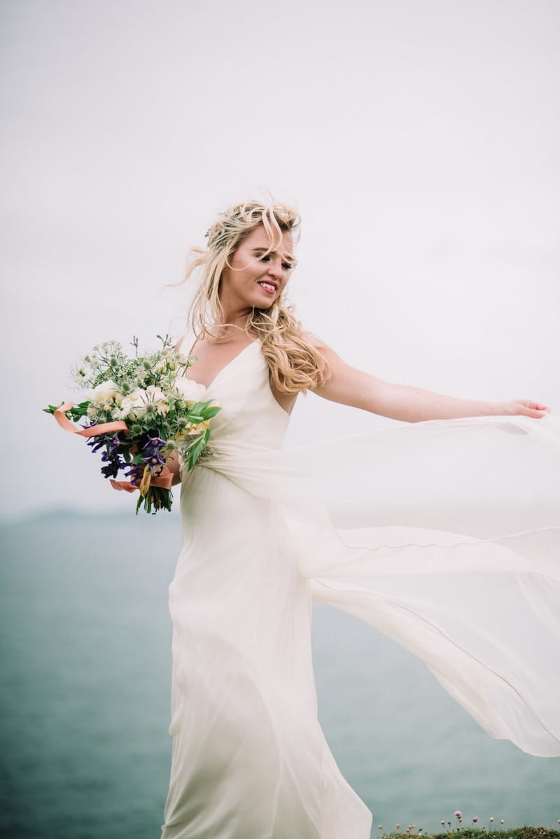 Bride holding out dress as it blows in the wind