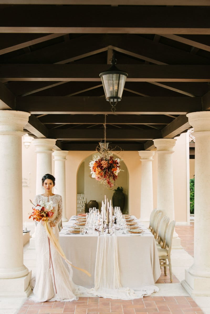 Bride standing holding bouquet in front of elegant wedding table