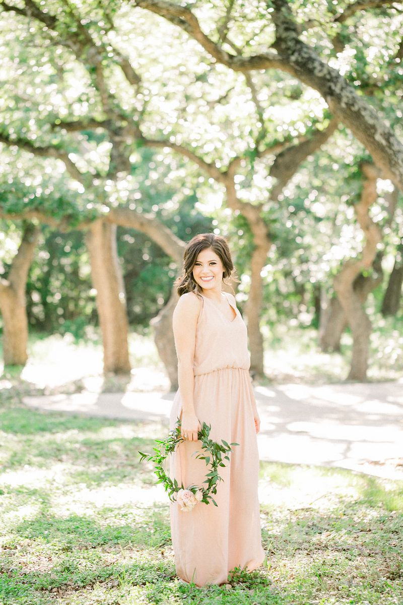 Bridesmaid in peach dress holding foliage hoop