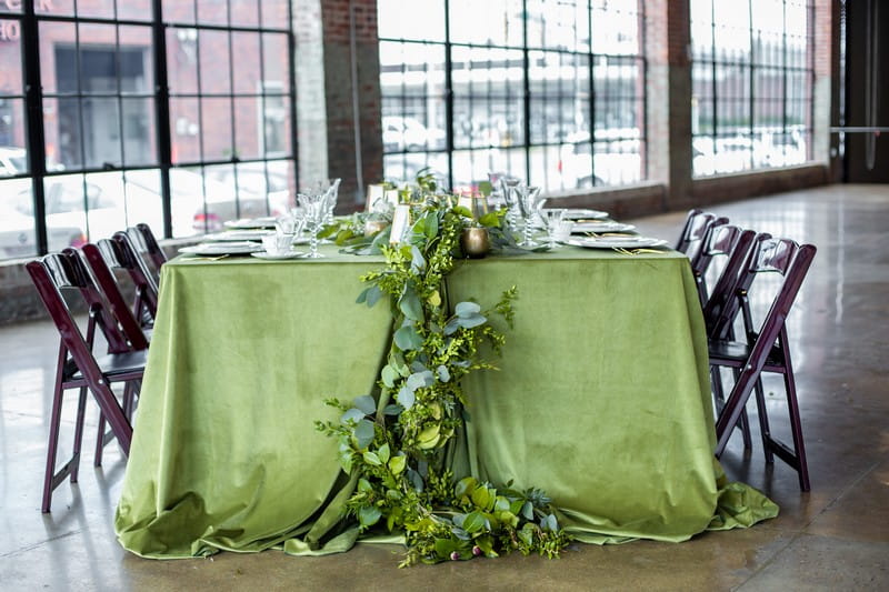 Foliage hanging off end of wedding table with green tablecloth