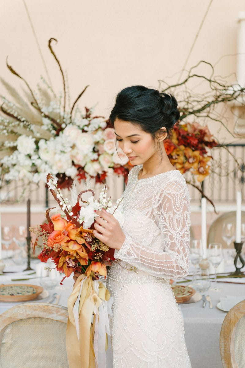 Bride holding autumnal bouquet in front of elegant wedding table