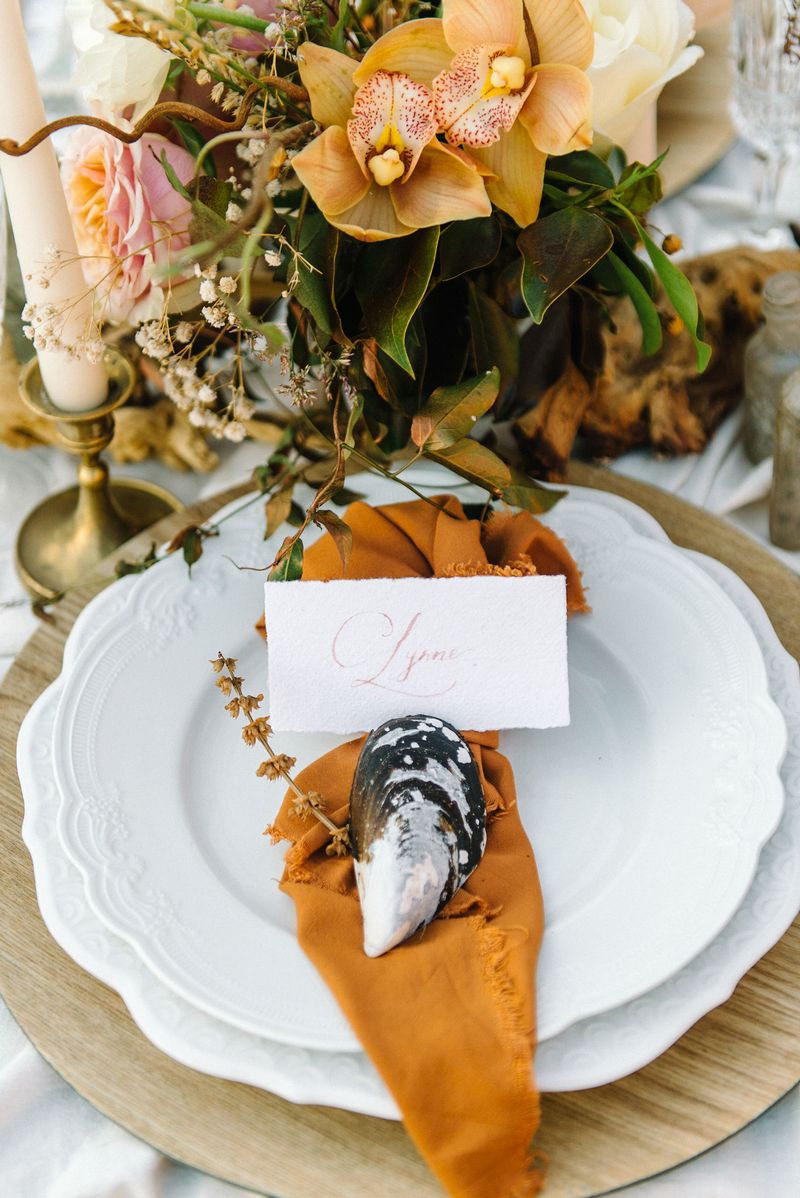 Wedding place setting with rust coloured napkin and sea shell