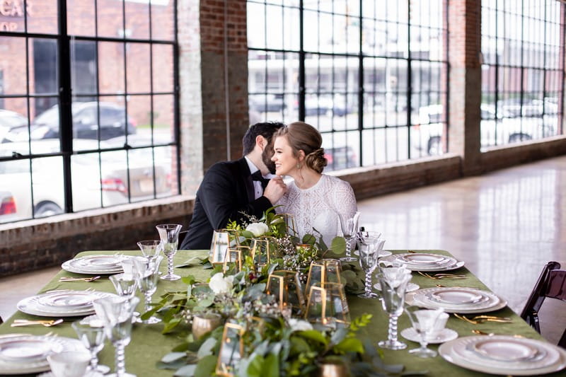 Bride and groom sitting at wedding table with foliage runner