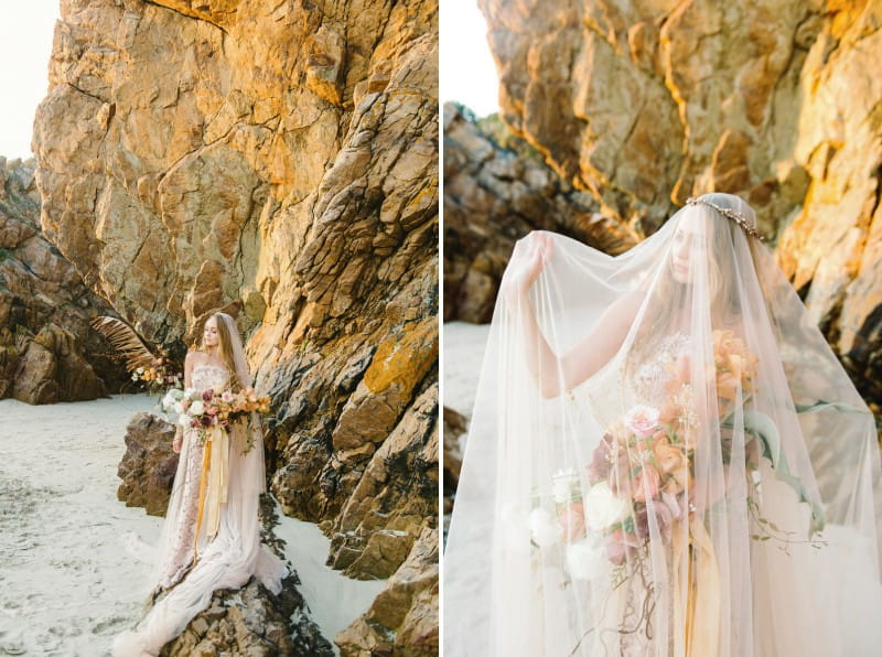 Bride standing on rocks on beach with veil over her face