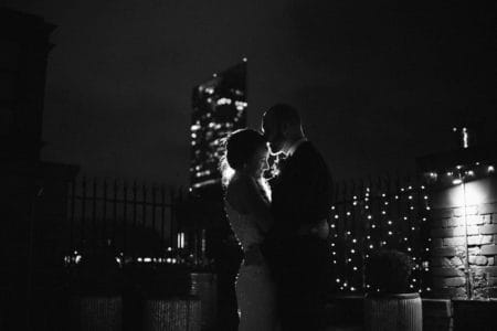 Bride and groom hugging at night with tall building in background - Picture by Rebecca Parsons Photography