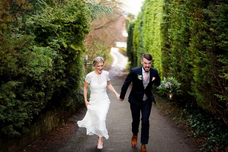 Groom grimacing as he walks up steep hill with bride - Picture by Carine Bea