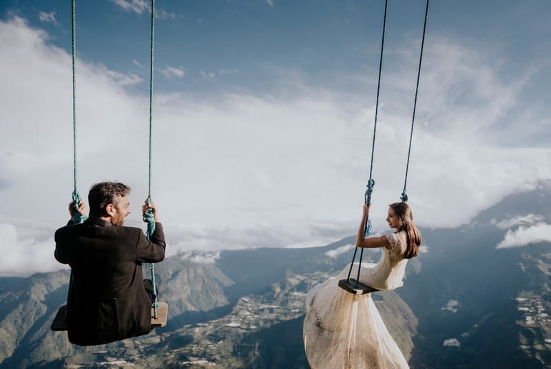 Bride and groom sitting on swings overlooking mountains - Picture by Daniel Maldonado Photography