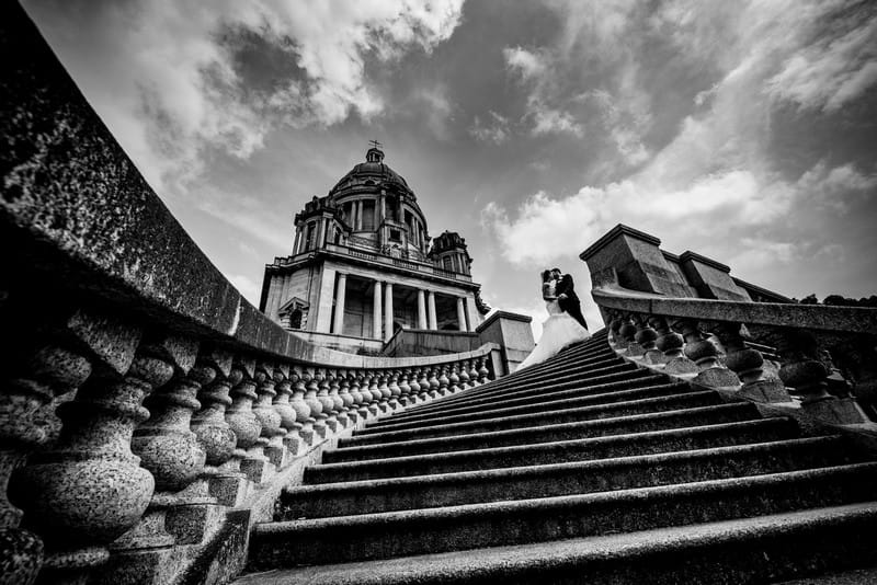 Bride and groom at top of sweeping steps outside wedding venue - Picture by James Tracey Photography