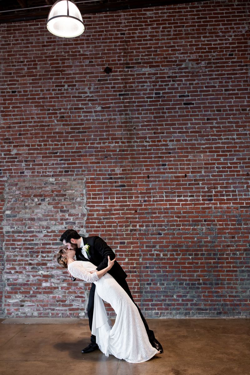 Groom leaning bride back to kiss her