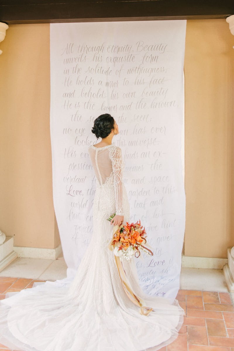 Bride standing in front of long material backdrop with writing on it