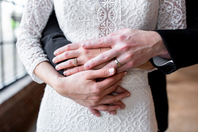 Bride's hands on top of groom's around her waist