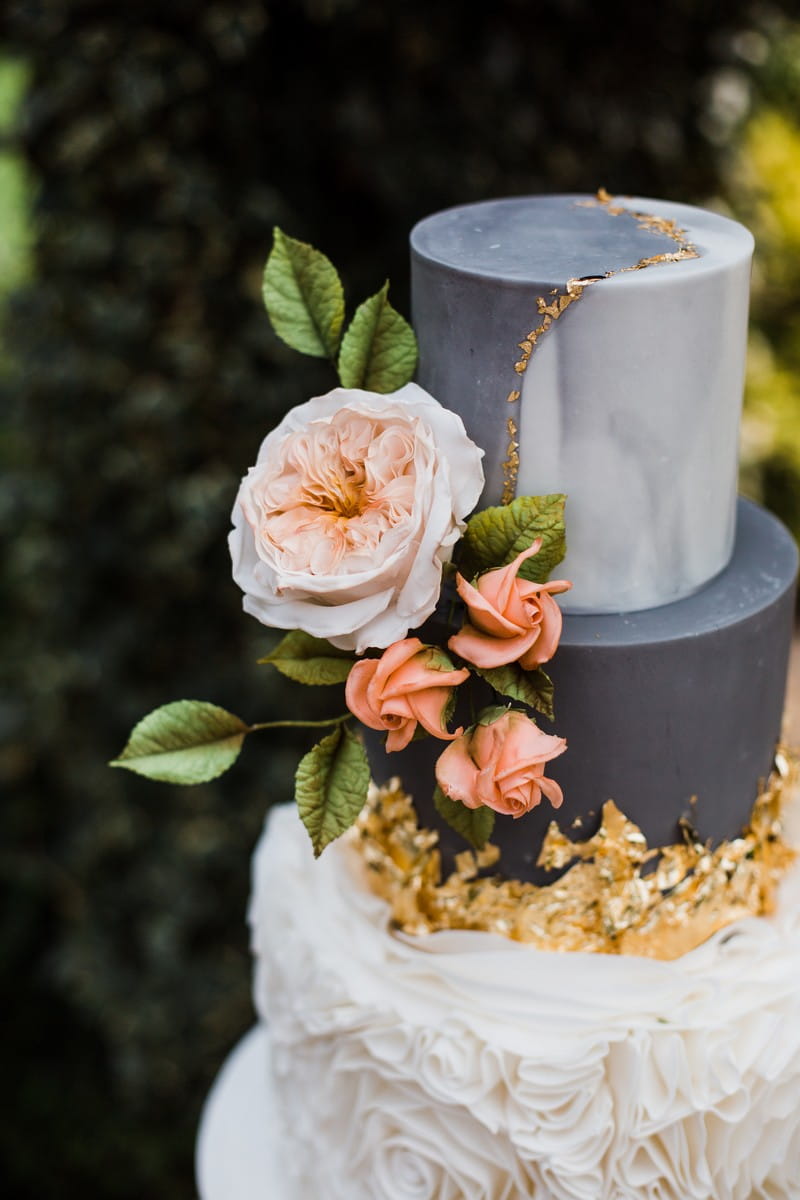 Coral flowers and gold leaf on wedding cake